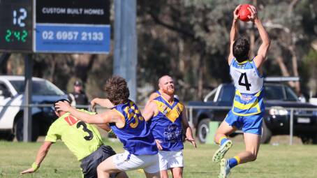 MCUE forward Flynn Collins takes an uncontested mark while umpire Symon Tardrew is collected by Narrandera defender Stirling Kable during the Goannas win at Mangoplah Sportsground.