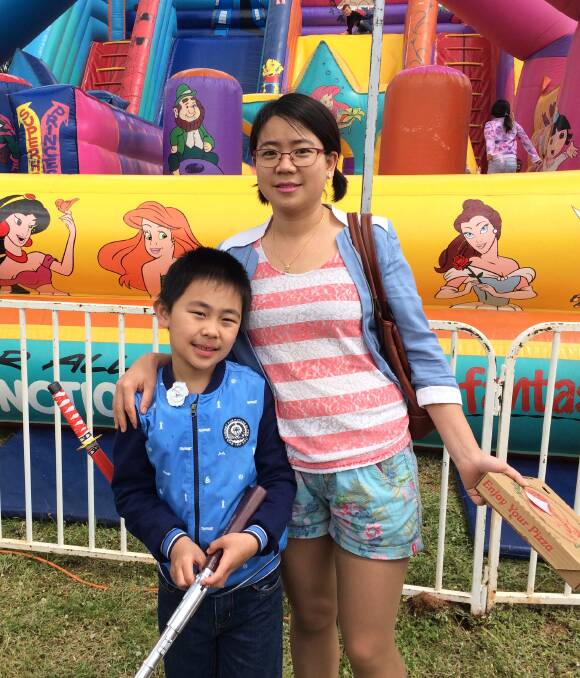 TAKING IT ALL IN: Brendan Yap and Emily Yin soak up the atmosphere in front of the bouncy castle at the 128th Junee Show on Saturday. The show attracted approximately 1700 people across the day. 