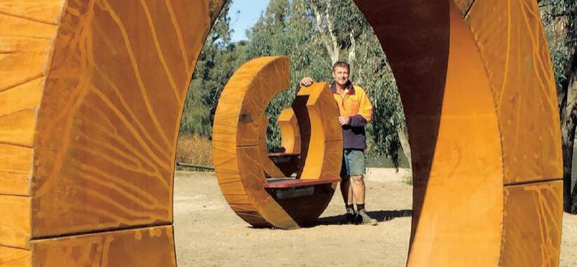 SCULPTURAL SEATING: Oura Beach's new wooden seating artwork, as displayed by aptly named Wagga artist John Wood. Picture: Wagga City Council 