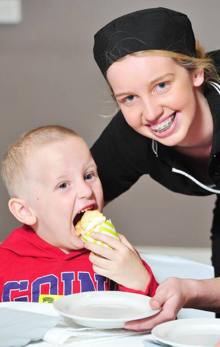 PURE ENJOYMENT: Brody Ogg, 4, gives a tick of approval to older sister Sharni Ogg's butterfly cake as Mount Austin High School hosted a high tea. Picture: Kieren L Tilly