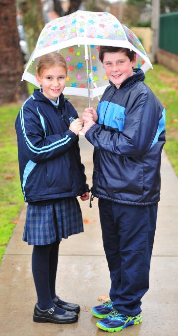 RAINY DAZE: Wagga Public School students Abbey Moore, 9, and Isaac Lofts, 11, keep dry from the wet weather in July. Picture: Kieren L Tilly