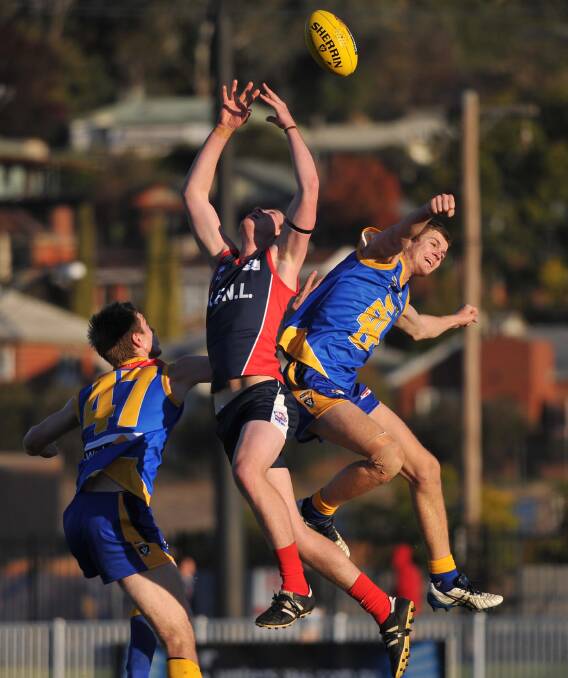 UP IN THE AIR: Riverina's Matt Collins flies despite close attention from Tallangatta's Rhys Hensell (right) and John Willis at Robertson Oval on Saturday. Picture: Laura Hardwick