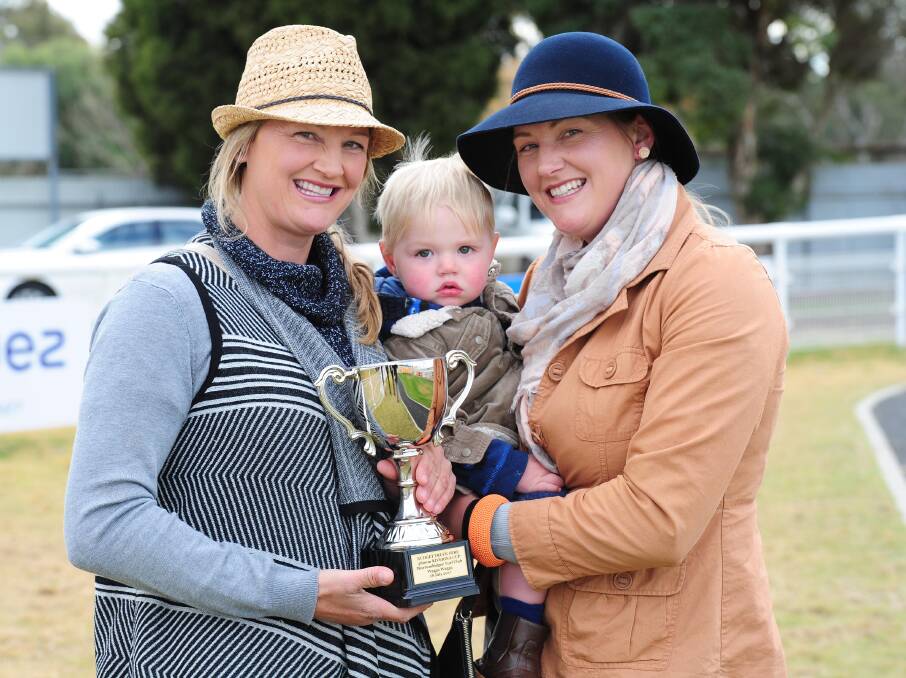 SISTERS' SUCCESS: Lucy (left) and Emma Longmire, with 16-month old Koda Langbien, show off their Riverina Cup at Murrumbidgee Turf Club on Tuesday. Picture: Kieren L Tilly