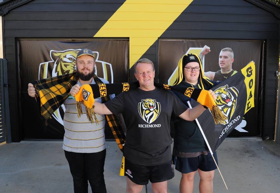 YELLOW AND BLACK: Wagga painter Shaun Coote with sons Harrison and Thomas show off their new look garage in time for Saturday's AFL grand final. Picture: Les Smith