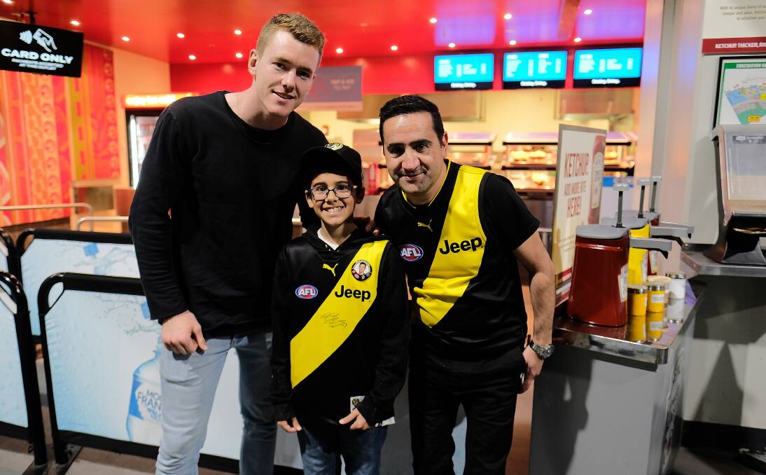 BIG WEEK: Leeton's Jacob Townsend poses with Richmond fans Ryan, 13, and Armando Scalzo at the VFL grand final on Sunday. Picture: AAP