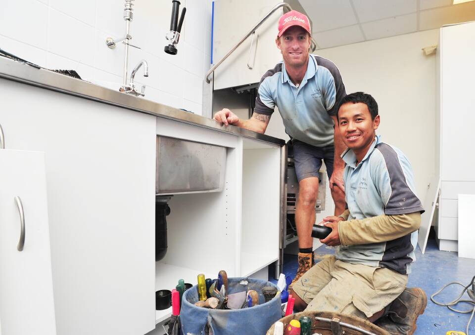 ELBOW GREASE: Plumber Andrew Smith and his second-year apprentice Janaw Share  hard at work on the job on Thursday. Picture: Kieren L Tilly