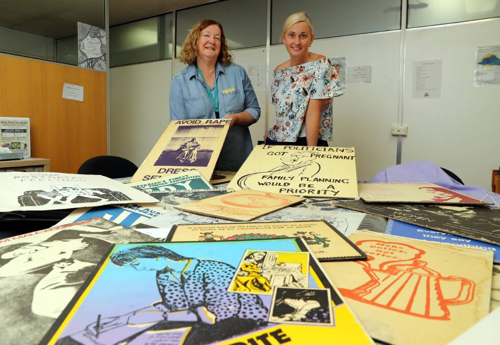 LOOKING BACK: Wagga Women's Health Centre manager Gail Meyer and finance officer Alison Carr pour over posters from the last four decades. Picture: Les Smith