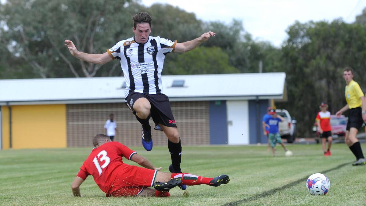 TOUGH CHALLENGE: Wagga City Wanderers player Alex Millour jumps over Avalon's Barry Tompkins in last year's FFA Cup.