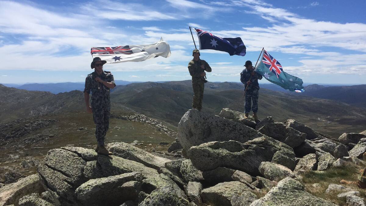 ON TOP OF THE WORLD: Wagga's Lachlan Pagett, Blake Malligan and Brandon McHugh fly flags on top of Mt Kosciuszko at the weekend.