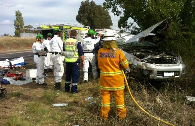 HORROR CRASH: VRA and Tarcutta RFS volunteers attend to a horror crash on the centre verge of the Hume Highway on Monday.