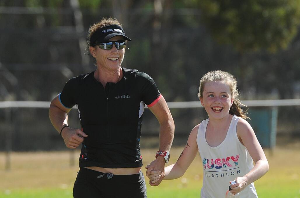 HAPPY DAYS: Women's winner Briony Mazzocchi and daughter Ally, 8, cross the finish in The Rock triathlon on Sunday. Picture: Laura Hardwick