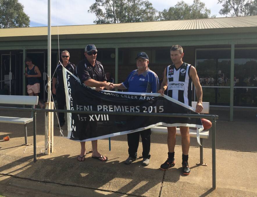 SOMETHING TO CELEBRATE: TRYC president Gavin Hofert (left) is congratulated by Farrer League president David Oehm while last year's victorious coach David Pieper holds the flag. As the Pies played out a draw with EWK, the unfurling of the flag was the only celebration.