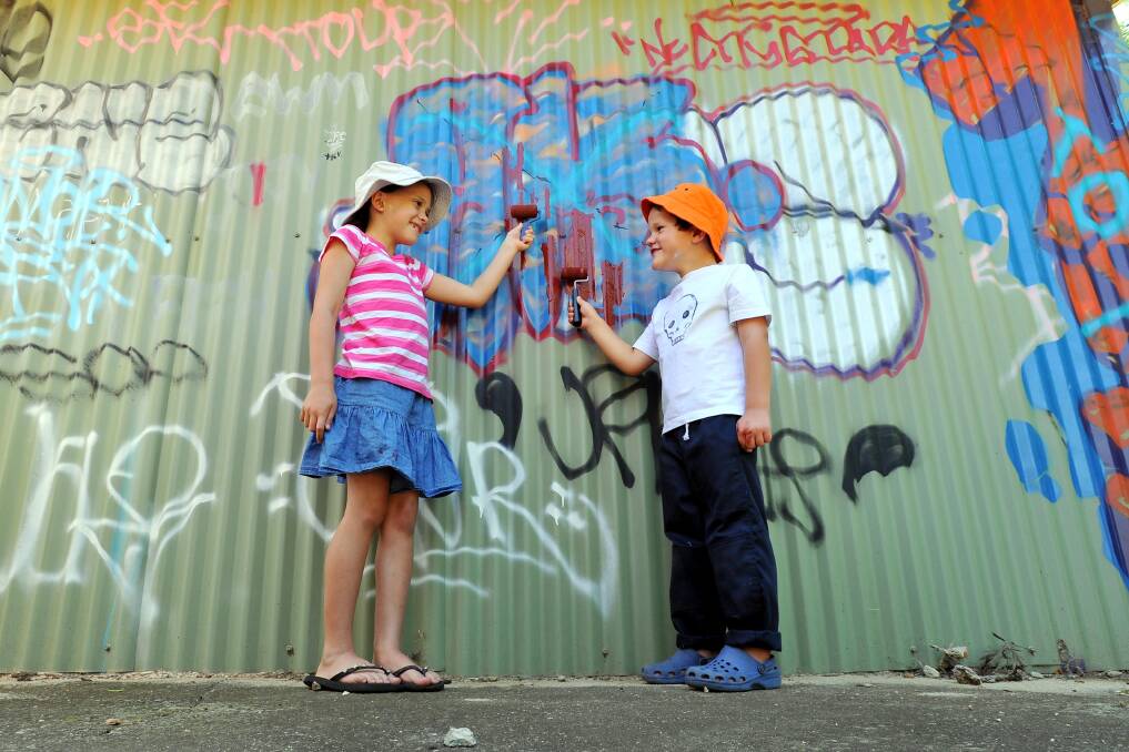 NOT ON: Grace Higgins, 8, and Tyrone Higgins, 5, play their hand in Graffiti Removal Day at the Wagga Volunteer Rescue Association shed on Docker Street. It was one of 25 clean-up sites in the city. Picture: Les Smith 