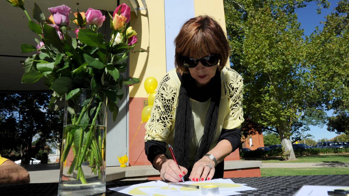 Leeton's Di Frazer pauses to sign a book remembering Stephanie Scott. Picture: Anthony Stipo