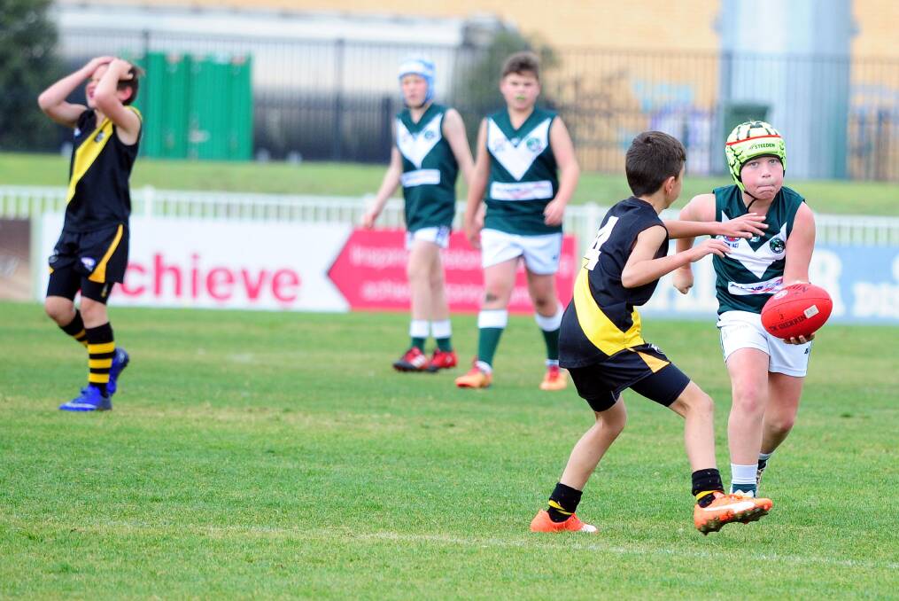 IN TROUBLE:  Lachlan Fifield gets a hand pass away in the under 11's Australian rules as Wagga Tigers play Coolamon at Robertson Oval on Saturday. Picture: Kieren L. Tilly