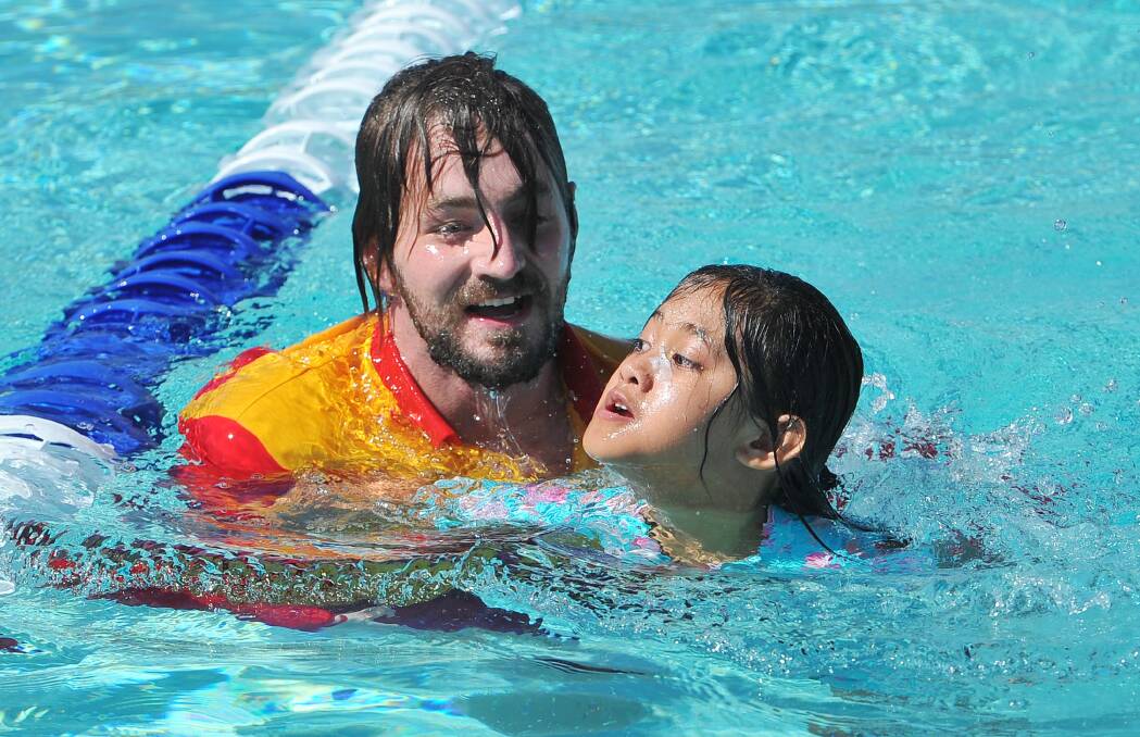 NOTHING'S IMPOSSIBLE: Lifeguard Phil Stone jumps in and helps Alina Flores, 10, to finish the race at the Sturt Public Swimming Carnival . Picture: Kieren L. Tilly