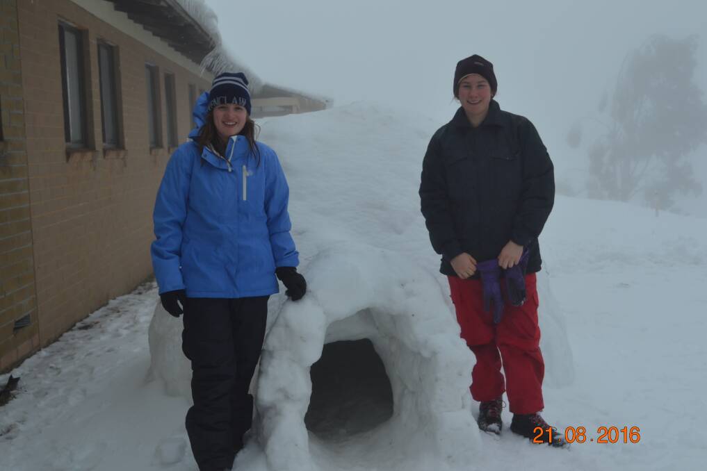 COLD COMFORT: Holly Mack and Lily Carroll of 1st Wagga Scouts emerge from their igloo adventure.