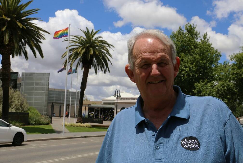 As seen on Twitter: Mayor Greg Conkey stands in front of a rainbow flag, flown outside council chambers. 
