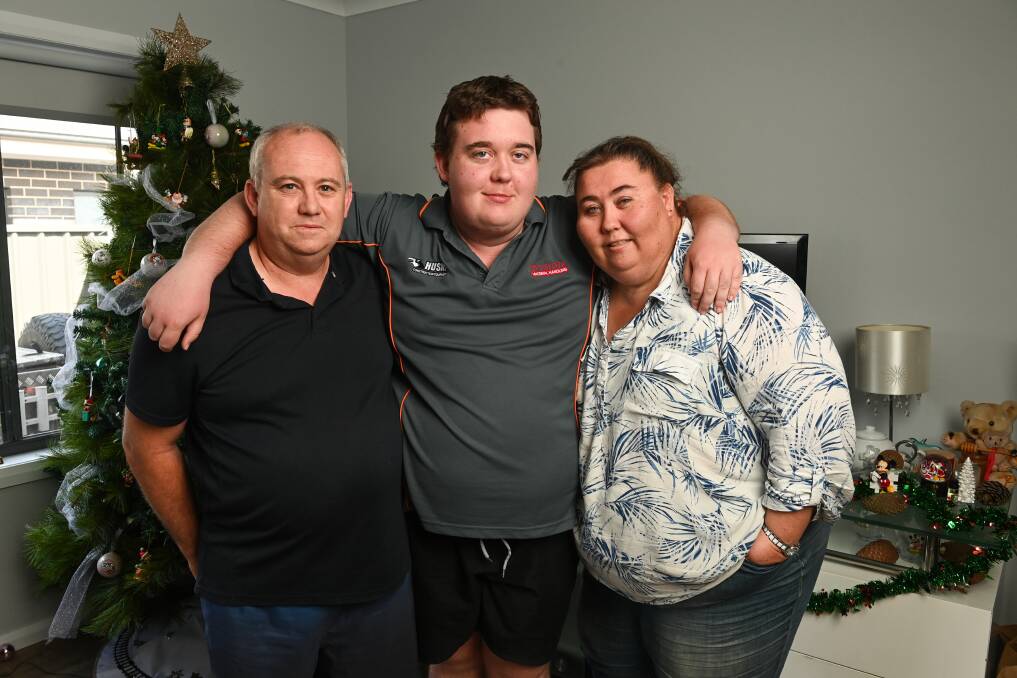 Encephalitis survivor Dylan Meyer embraces his stepfather Brendan Saunders and Debra Meyer-Saunders as they prepare for what will be a special Christmas after an arduous year. Picture by Mark Jesser