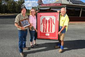 Pleasant Hills locals Rick Clancy, Fiona Beckett and Peter Sharp outside the village's community hotel with some memorabilia from the footy club. Picture by Mark Jesser