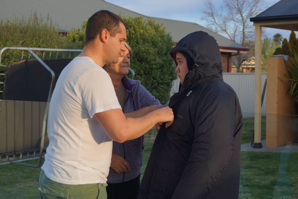 Loved: Geoff Seymour helping his son, Jaz, put on anther jacket with Jaz's grandmother also helping. 