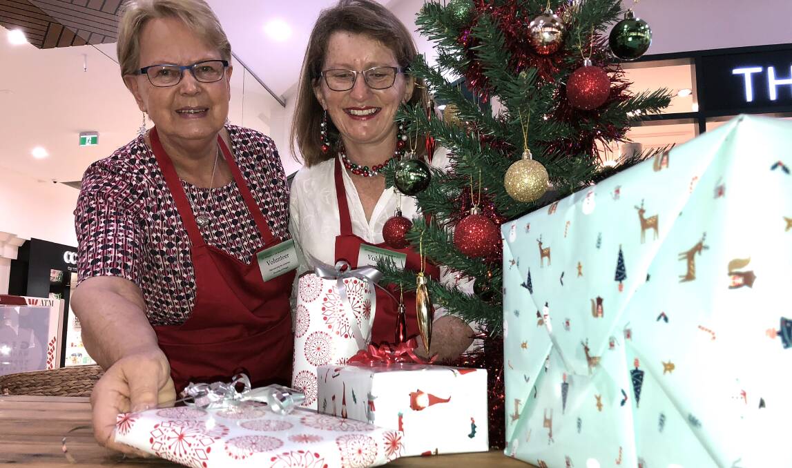 VOLUNTEERS: Annette Howard and Traci Wrenford at the Wagga Marketplace stand, where people can drop off their presents and have them wrapped for a gold coin donation.