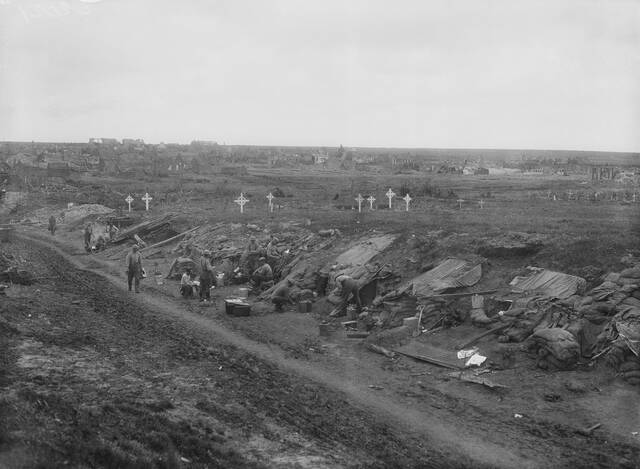 Troops billeted in a sunken road near Bullecourt. Graves with headstones are in the field beyond the road. Picture: Australian War Memorial