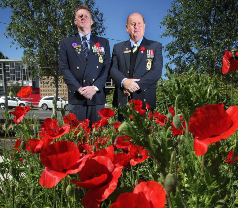 BUY A POPPY: Wagga RSL sub-branch committee members Ray Smith (left) and Brian Watts amid real red poppies in the Victory Memorial Gardens. Picture: Les Smith