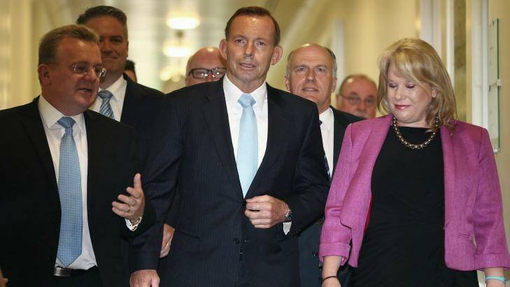 Flanked by MPs, Prime Minister Tony Abbott leaves the party room meeting on Monday. Photo: Alex Ellinghausen