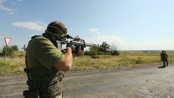 Pro-Russian rebel sniper 'Angel' 43 looks through the scope of his gun at a checkpoint on the outskirts Shakhtersk and aims over the shoulder of locals.  Photo: Kate Geraghty