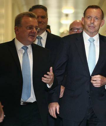 Flanked by MPs, Prime Minister Tony Abbott leaves the party room meeting on Monday. Photo: Alex Ellinghausen