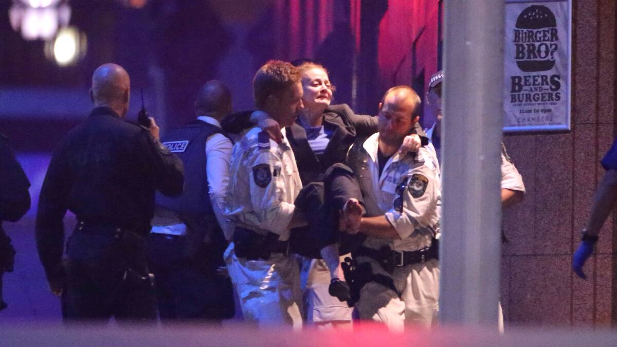 Hostages are assisted from the Lindt Chocolat Cafe in Martin Place. Photo: Andrew Meares