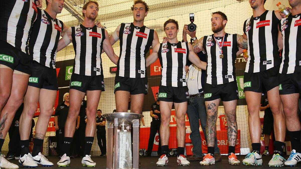 Magpies players celebrate their win around their Anzac Day trophy. Photo: Getty Images. 