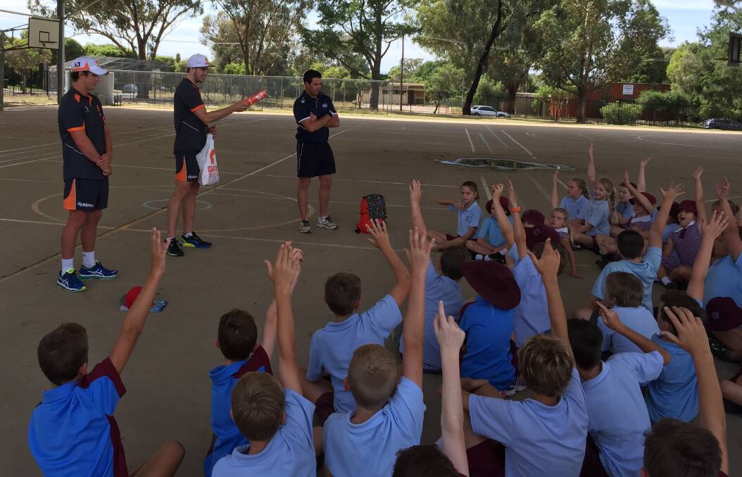PICK ME: Students at Kooringal Public School throw up their hands to answer a question from Greater Western Sydney footballers Jake Barrett (left) and Lachie Plowman (middle) on Monday. Picture: Matt Malone