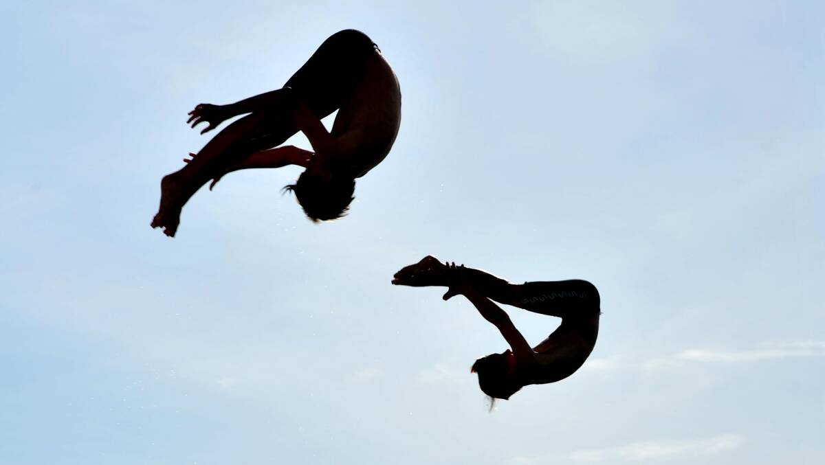 DIVE TIME: Wagga Diving Club members  Angus Grigg, 12, and his brother Edouard Grigg, 11, perform\ spectacular unison dive at the Oasis Regional Aquatic Centre on Monday. Picture: Michael Frogley


