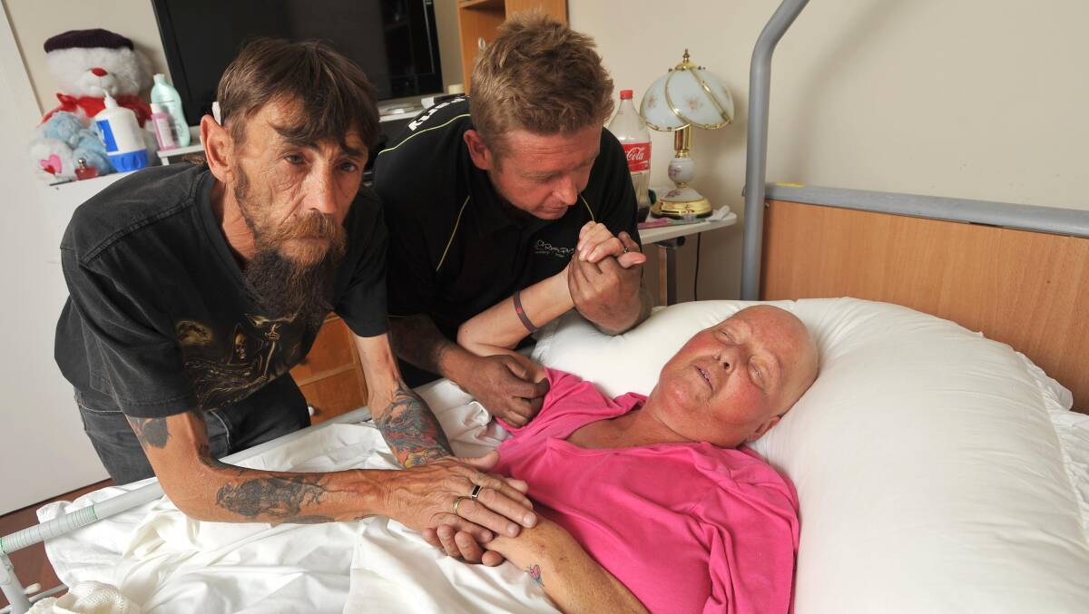 DESPERATE: (from left) Husband Michael Kelly and son Steven comfort Sue, who is dying from cancer and unable to live her final days in her own home. Picture: Laura Hardwick 