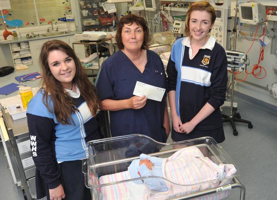 BALL FOR A CAUSE: Wagga High School students (left) Clara Bate and (right) Chloe Harpley present Wagga Base Hospital maternity ward nurse midwife (centre) Clare Fitzgerald  with the near $6000 they raised at their school ball, while baby Austin Harris watches on. Picture: Michael Frogley