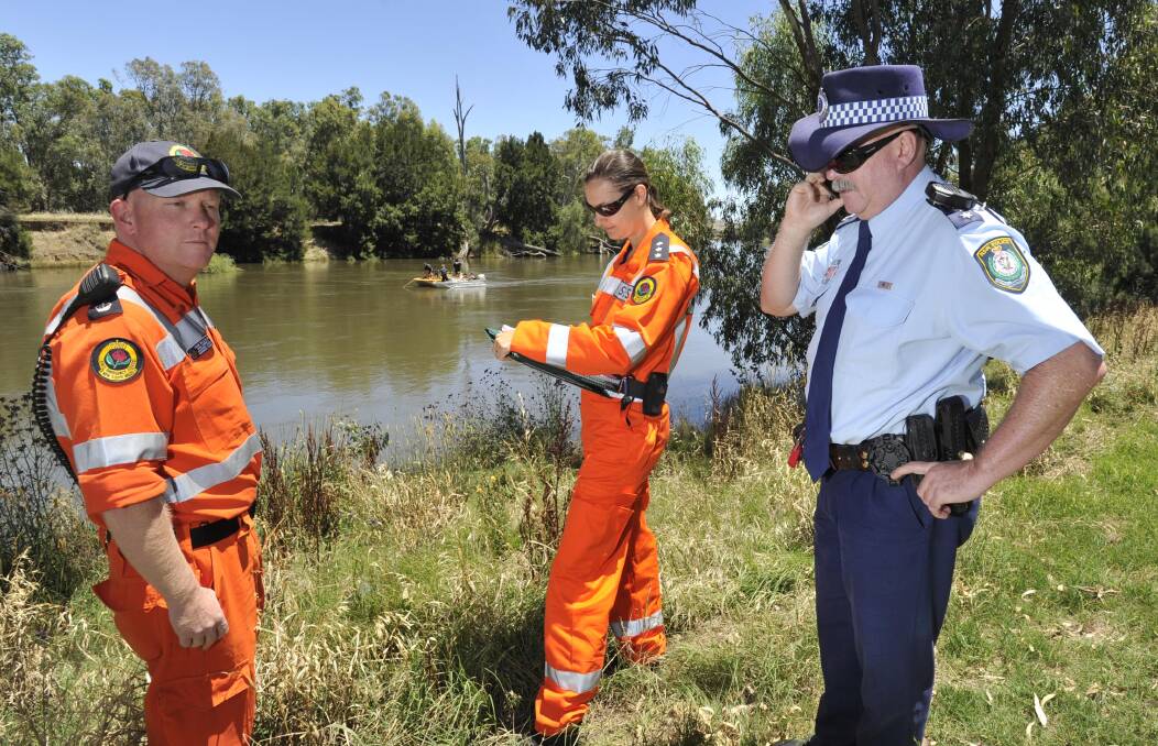SEARCH PARTY: Inspector Peter Robertson with SES volunteers Shane McLachlan and Rebecca Milne on the bank of the Murrumbidgee River at Oura as police divers in a boat use sonar equipment to search the river for a missing man. Picture: Les Smith