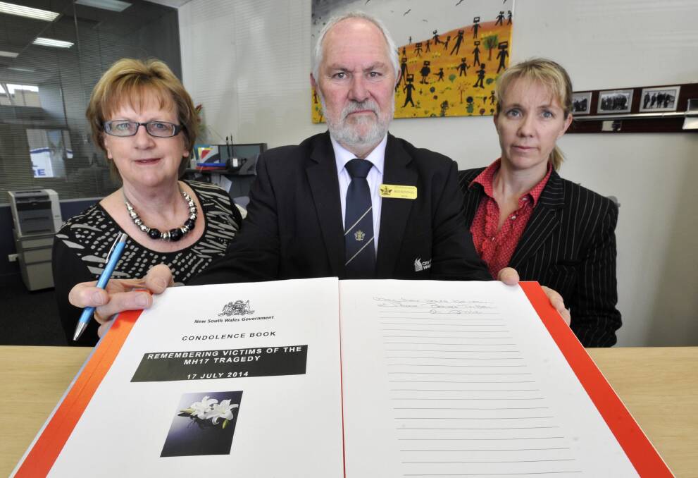 CONDOLENCES: With a MH17 condolence book are Wagga mayor Rod Kendall and Wagga electorate officers Margaret Pulver (left) and Susan Schiller. Picture: Les Smith