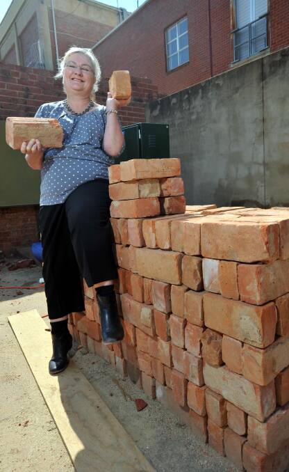 GOOD CAUSE: Jenny Mountford with some of the old jail wall bricks for sale at $10 each, with money going to Sunflower House. Picture: Michael Frogley
