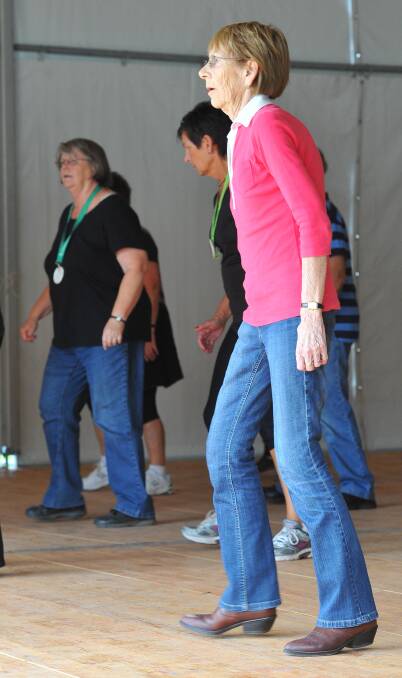 Wagga's Wendy Griffin assists a line dancing class being taught by Boots n Buckles at the Stone the Crows Festival on Good Friday. Picture: Kieren L Tilly