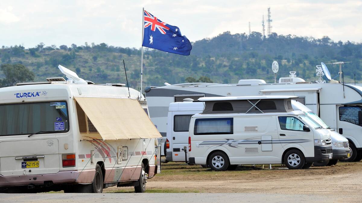 An Australian flag flutters in the breeze as Willans Hill backdrops the many vehicles camped at the Stone the Crows Festival in Wagga on Good Friday. Picture: Kieren L Tilly