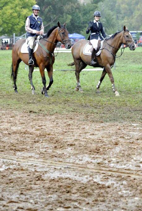 Canberra showjumping competitors Cecil Staples and Steph Davies dodge the mud in the main arena at the Gundagai show. Picture: Les Smith