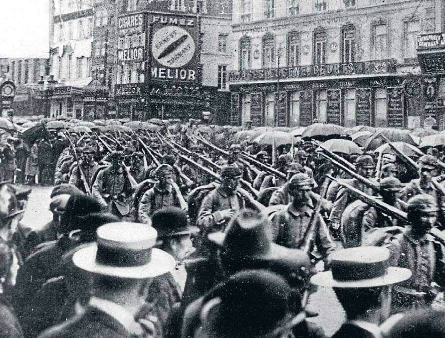 Crowds gather in the Place Rogier, Brussels, in the rain to watch German troops as they march into the Belgian capital. Published 1914.