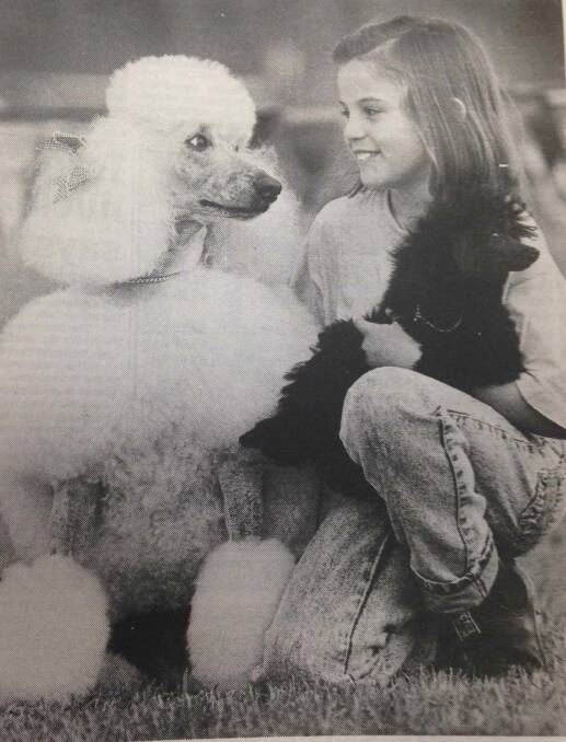 Tara Buik, 8 poses with her white standard poodle Beth and toy poodle pip Cassie at the Kyeamba Kennel Club dog show.