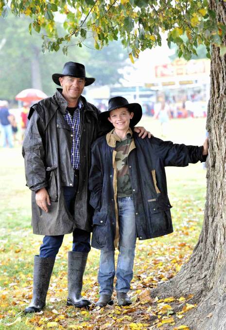 Bungendore's Jack Campbell and son Scott, 12, caught some shelter on the way to sideshow alley between rounds of the sheedog trials at the Gundagai show. Picture: Les Smith