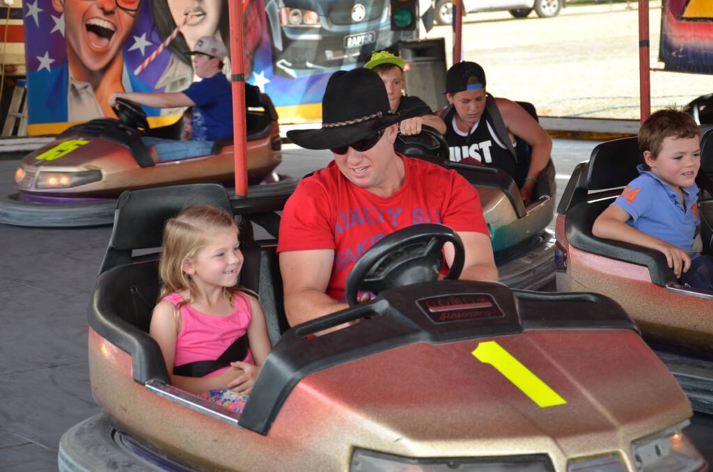 Ayla, 6, and Brad Nicoll take a turn on the dodge-em cars at the Junee Show. Picture: Declan Rurenga