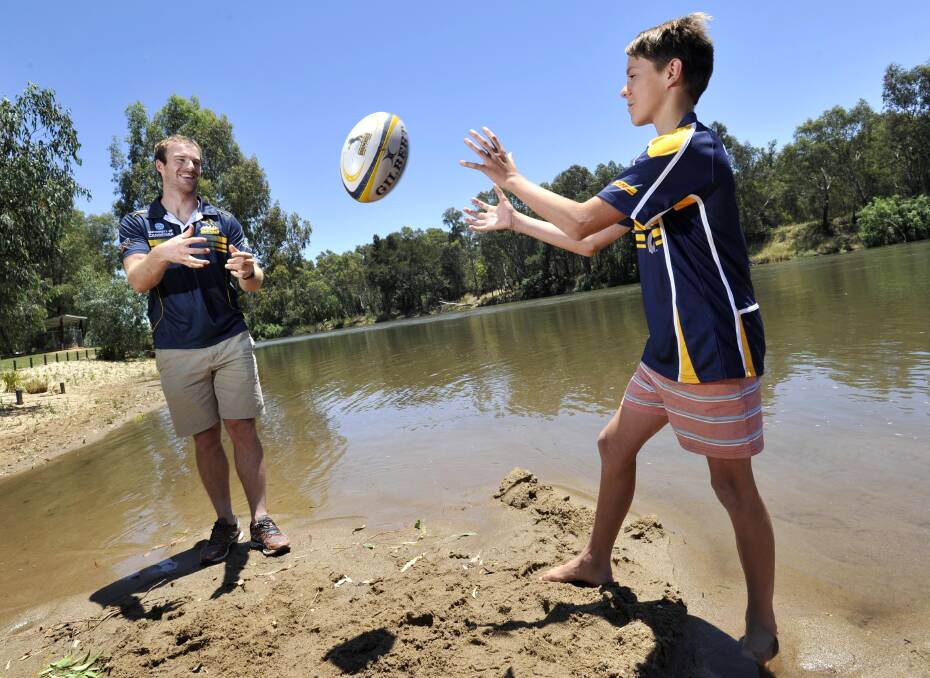 NEXT STEP: Former ACT Brumbies player Pat McCabe gives fan Hamilton McLaren, 13, a few pointers while at Wagga beach to launch ticket sales for the Super Rugby trial match next month. Picture: Les Smith