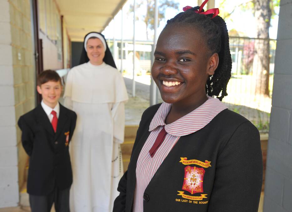Michael Curtis, 13, Sister Mary Dominica from the Conventual Sisters of St Dominic and Jackline Okot, 15, celebrate Saint Mary MacKillop College's stellar NAPLAN results.