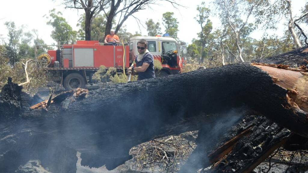 RFS volunteer Nathan Chanterill puts out hotspots on Thursday while West Wyalong resident Wayne Taylor assists from the fire truck. Picture: Hannah Higgins